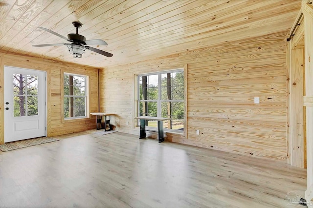 empty room with wooden walls, ceiling fan, wood ceiling, and wood finished floors
