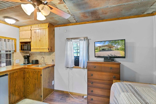 kitchen with decorative backsplash, wood finished floors, black microwave, ceiling fan, and a sink