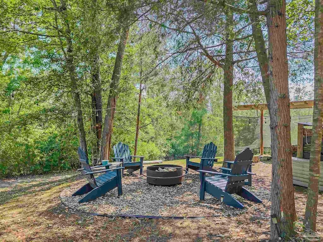 view of yard featuring a fire pit and a wooded view
