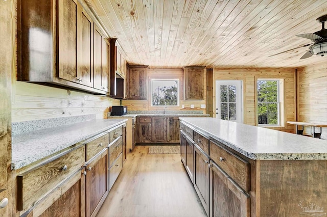 kitchen with a kitchen island, ceiling fan, wooden ceiling, and light wood-style floors