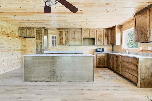 kitchen with wood walls, wooden ceiling, a sink, and light wood-style floors
