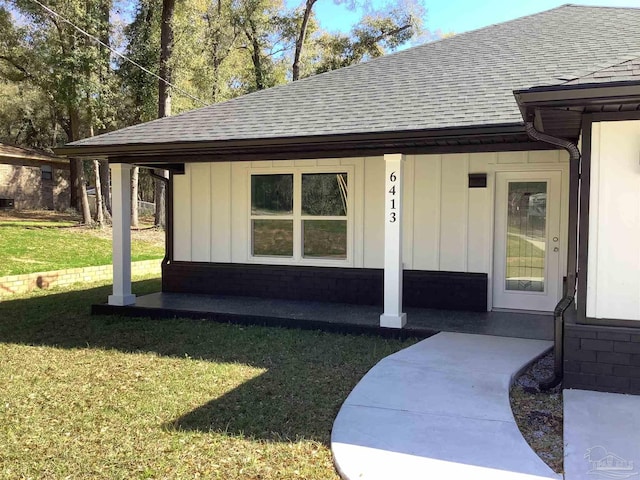 doorway to property featuring a lawn, a shingled roof, and board and batten siding