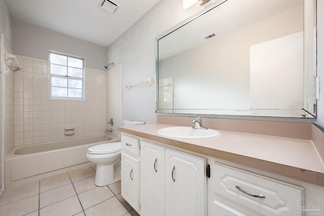 full bathroom with tile patterned flooring, vanity, tiled shower / bath combo, and toilet