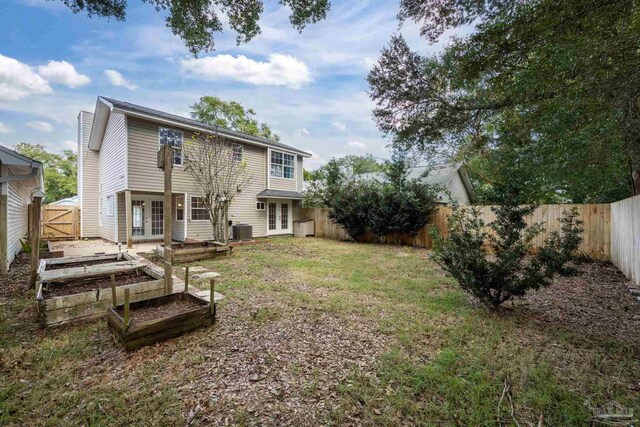 rear view of house with a lawn, french doors, and central AC unit