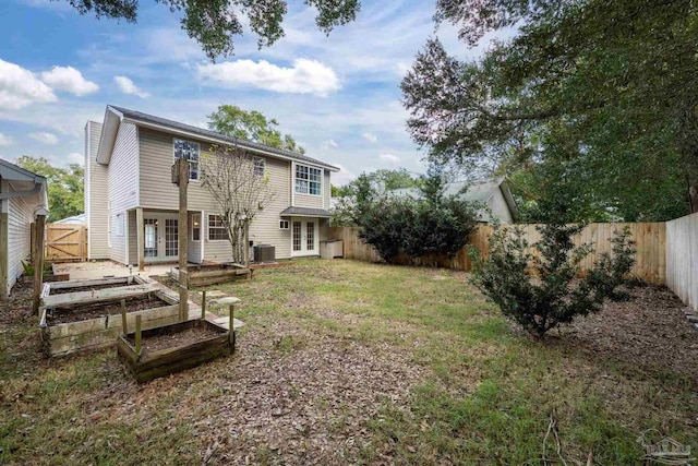 rear view of house with a lawn, french doors, and cooling unit