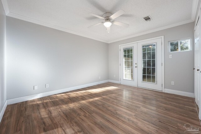 spare room featuring a textured ceiling, dark wood-type flooring, crown molding, and french doors