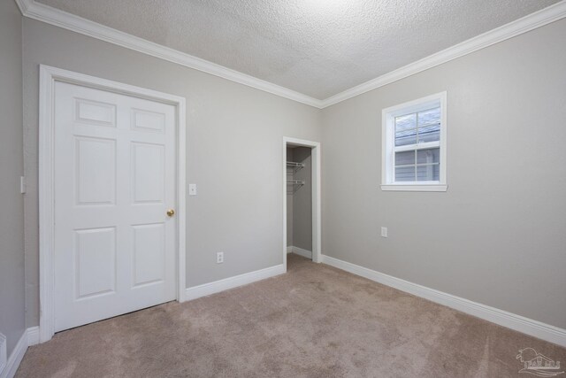 unfurnished bedroom with a closet, light carpet, crown molding, and a textured ceiling