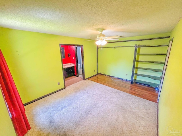 unfurnished bedroom featuring a textured ceiling, baseboards, carpet, and ensuite bathroom