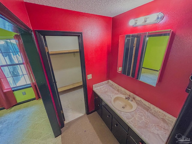 bathroom featuring a textured ceiling, a textured wall, and vanity