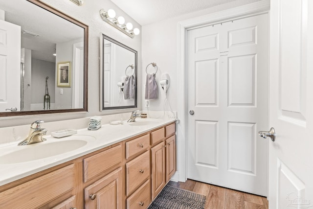 bathroom with a textured ceiling, vanity, and hardwood / wood-style flooring