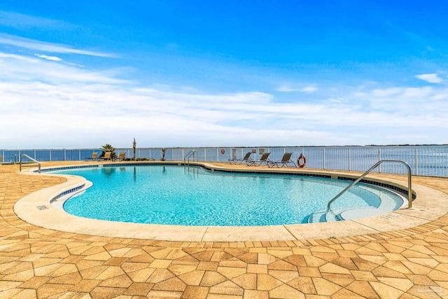 view of swimming pool with a patio and a water view