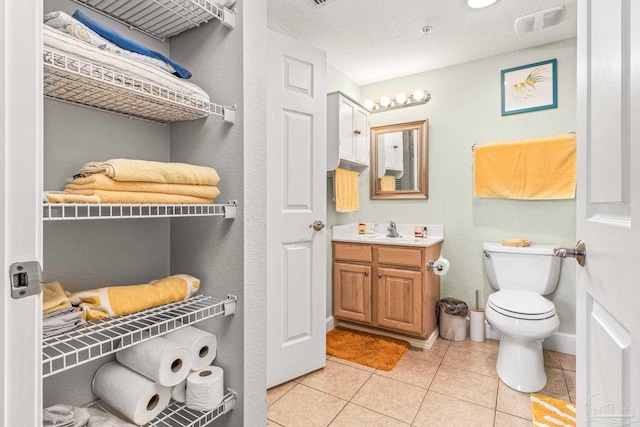 bathroom featuring a textured ceiling, tile patterned flooring, vanity, and toilet