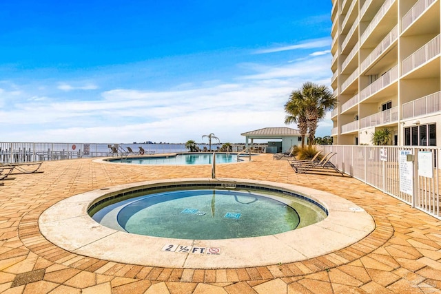 view of swimming pool featuring a hot tub and a patio area