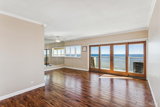 empty room featuring dark wood-type flooring, a water view, and a healthy amount of sunlight