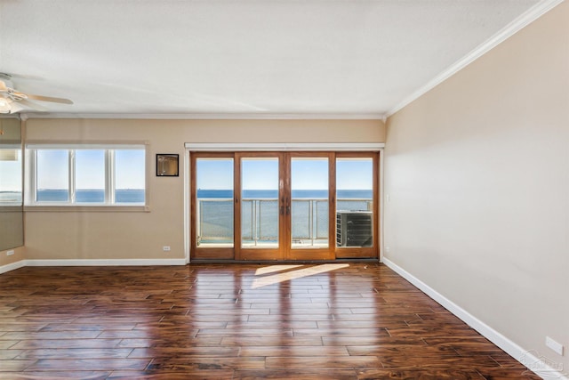 empty room featuring dark hardwood / wood-style floors, a healthy amount of sunlight, a water view, and crown molding