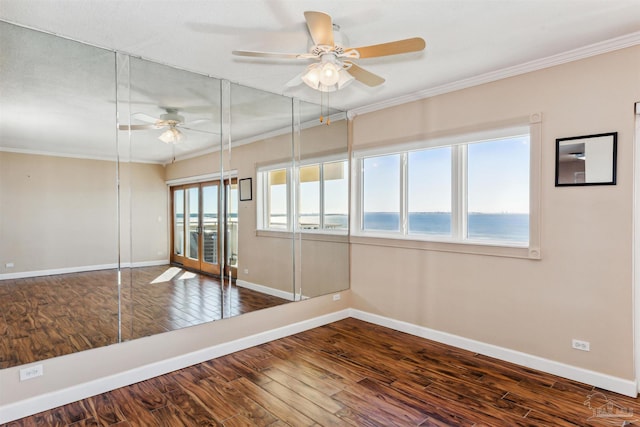 spare room featuring ceiling fan, a water view, wood-type flooring, and crown molding