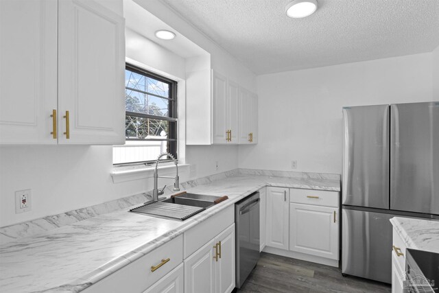 kitchen with stainless steel appliances, dark wood-style floors, white cabinets, a textured ceiling, and a sink