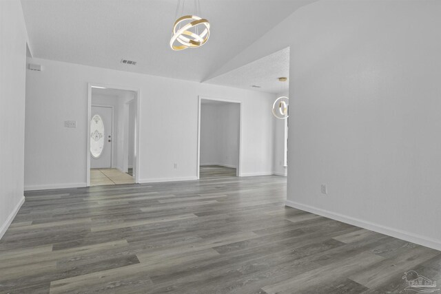 empty room featuring baseboards, lofted ceiling, and wood finished floors