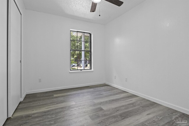 unfurnished bedroom with baseboards, a textured ceiling, and wood finished floors