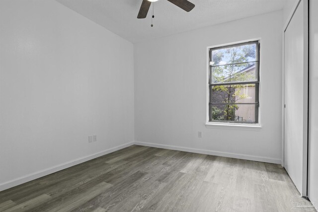 empty room with wood finished floors, baseboards, and ceiling fan