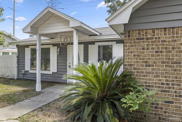 view of exterior entry with brick siding and fence