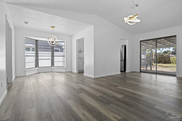 unfurnished living room featuring visible vents, a textured ceiling, dark wood-style floors, a chandelier, and vaulted ceiling