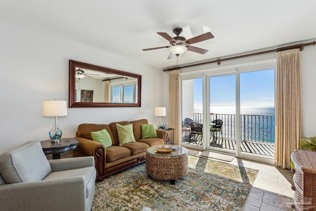 tiled living room featuring a water view and ceiling fan