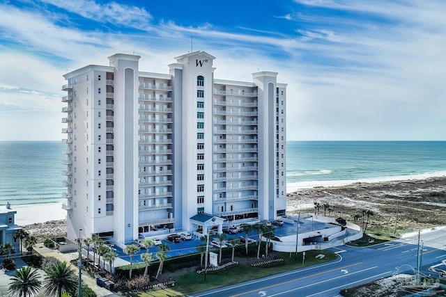 view of building exterior featuring a water view and a beach view