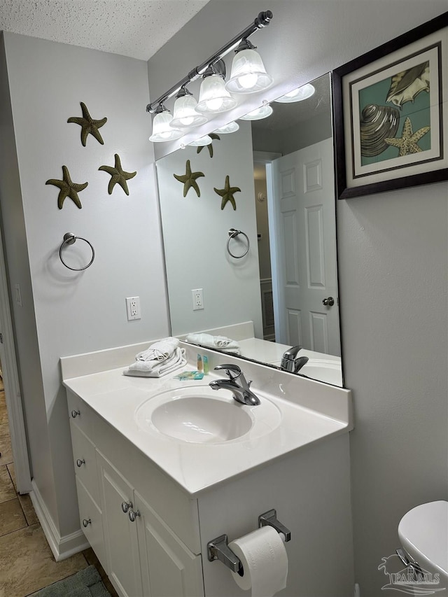 bathroom featuring tile patterned flooring, vanity, toilet, and a textured ceiling