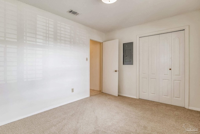 unfurnished bedroom with electric panel, carpet floors, and a closet