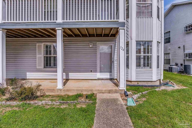 property entrance featuring a balcony, central AC unit, and a lawn