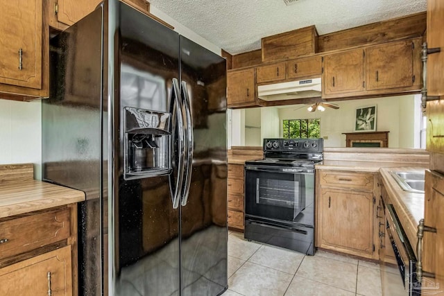 kitchen featuring a textured ceiling, black appliances, ceiling fan, light tile patterned floors, and sink