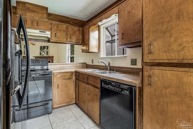 kitchen featuring light tile patterned floors, sink, black appliances, and a textured ceiling