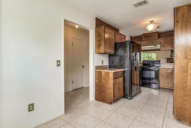 kitchen with a textured ceiling, black appliances, and light tile patterned floors