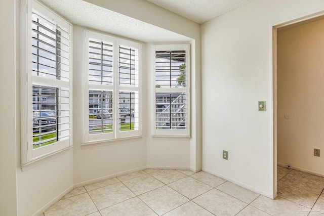 unfurnished room featuring light tile patterned floors and a textured ceiling