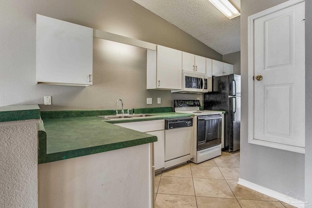 kitchen with white cabinets, light tile patterned floors, vaulted ceiling, sink, and white appliances