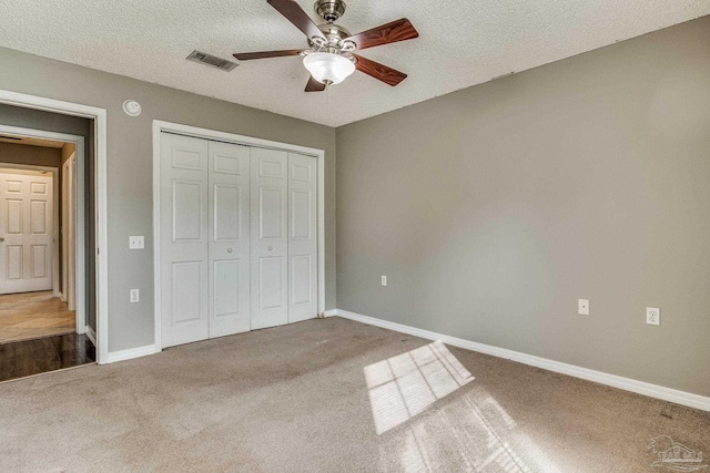 unfurnished bedroom with a textured ceiling, carpet flooring, a closet, and ceiling fan