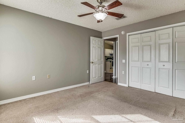 unfurnished bedroom with a closet, ceiling fan, carpet, and a textured ceiling