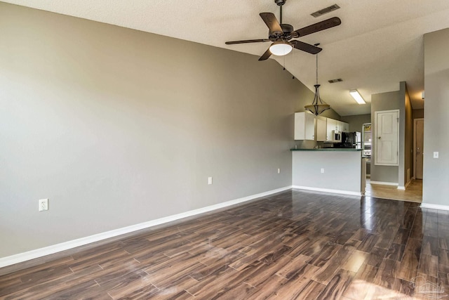 unfurnished living room with lofted ceiling, a textured ceiling, dark wood-type flooring, and ceiling fan