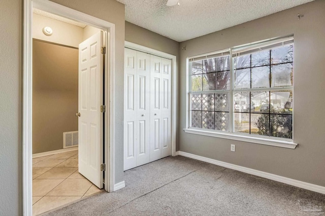 unfurnished bedroom with a textured ceiling, light colored carpet, and a closet