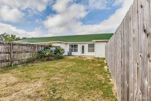 rear view of property featuring cooling unit and a yard