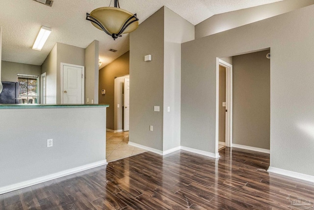 interior space with a textured ceiling, wood-type flooring, and lofted ceiling