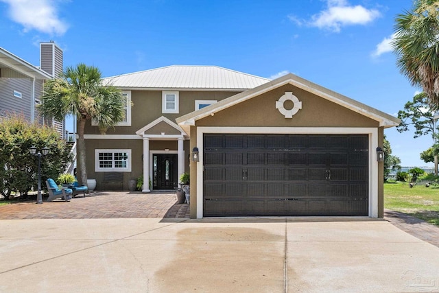 8209 Pompano St, Navarre, FL 32566 - view of front of house with stucco siding, driveway, a garage, and a metal roof