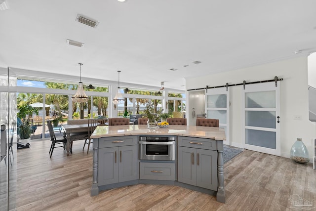 8209 Pompano St, Navarre, FL 32566 - kitchen with gray cabinetry, oven, a barn door, light wood-type flooring, and hanging light fixtures