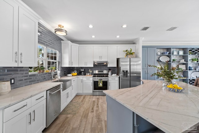 8209 Pompano St, Navarre, FL 32566 - kitchen featuring appliances with stainless steel finishes, light wood-type flooring, white cabinets, tasteful backsplash, and recessed lighting