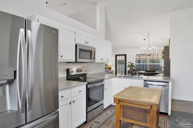 kitchen featuring decorative backsplash, vaulted ceiling, stainless steel appliances, white cabinetry, and a sink