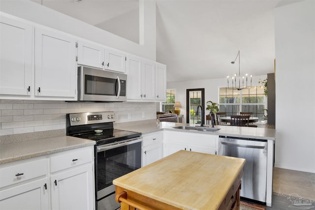 kitchen featuring tasteful backsplash, light countertops, appliances with stainless steel finishes, white cabinets, and a sink