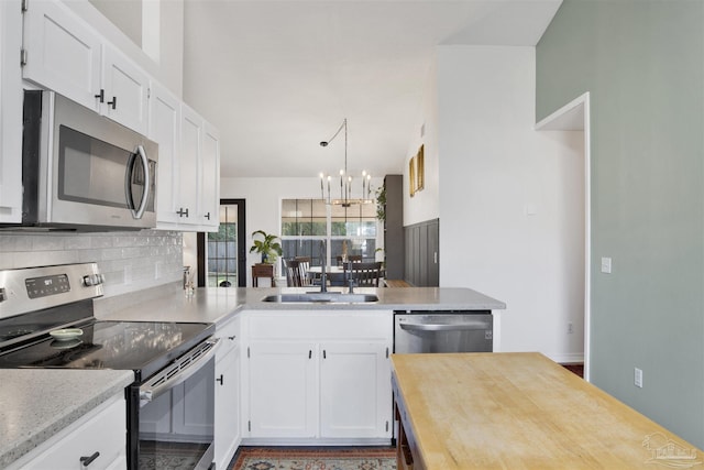 kitchen featuring stainless steel appliances, white cabinets, backsplash, and an inviting chandelier