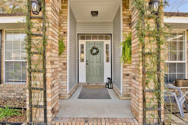 property entrance featuring a porch and brick siding