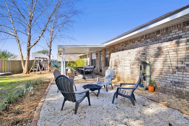 view of patio / terrace with an outdoor fire pit, a playground, and fence